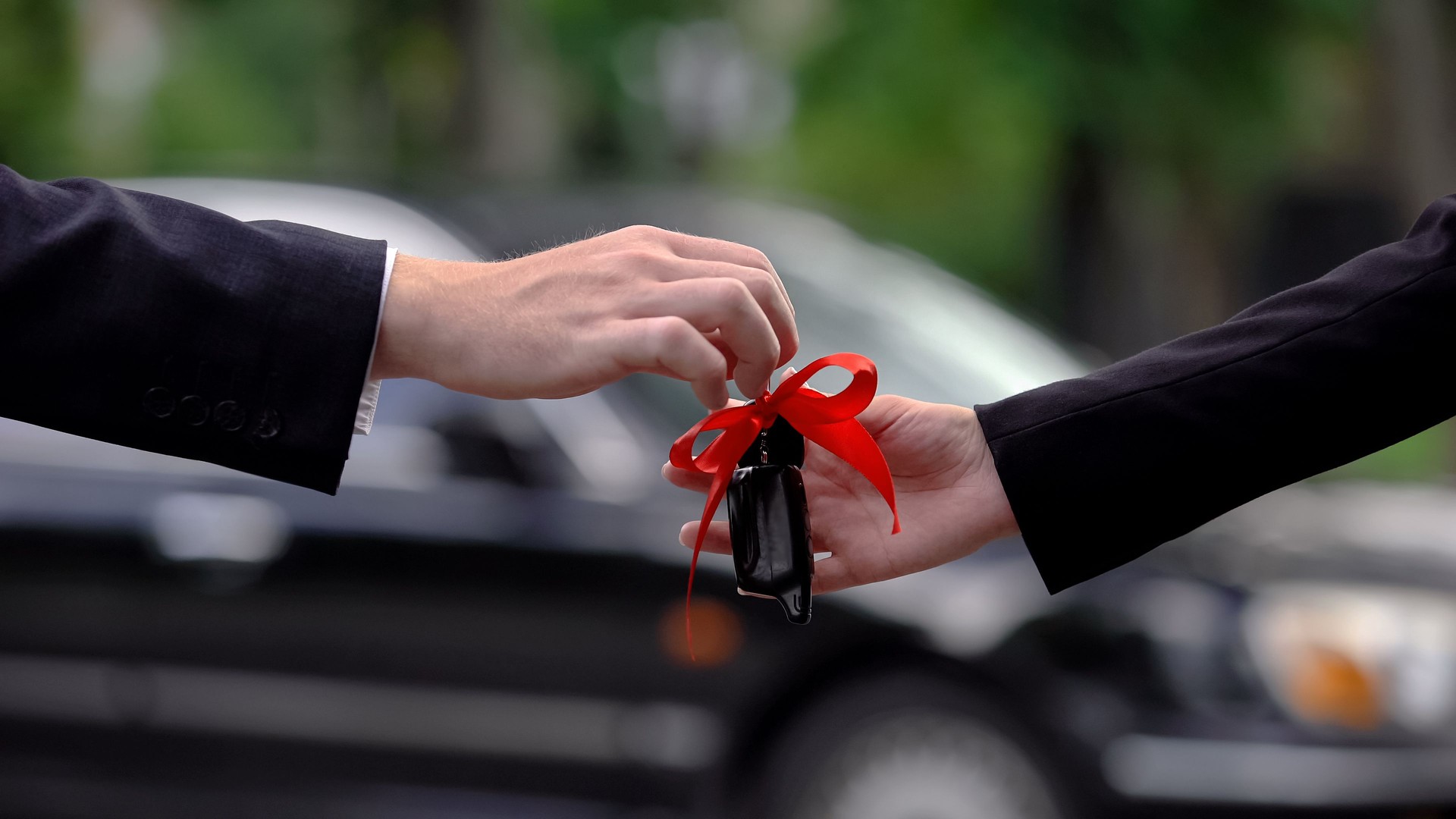Donna che prende la chiave dell'auto con nastro rosso dalla mano del rivenditore, acquisto di trasporto, affitto